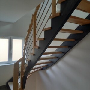 Escalier en frêne sur limon mural et crémaillère avant laqués noir Escalier en frêne sur limon mural et crémaillère avant laqués noir. Garde corps vernis avec poteaux droits, main courante arrondie sur le dessus et 3 lisses inox horizontales.